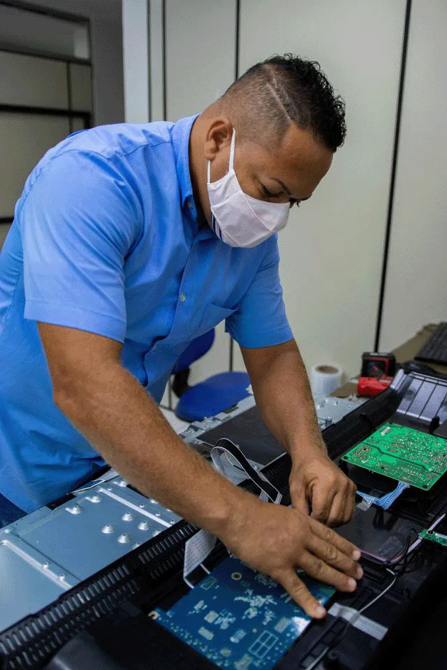 Técnico da Eletrônica TV Vídeo avaliando TV com manchas na tela em Salvador